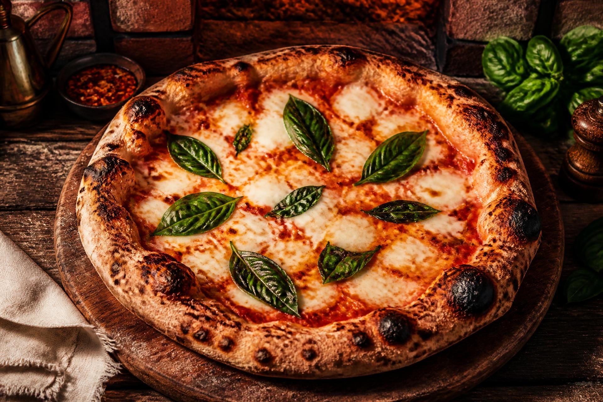 Nybakad pizza på träbräda i vedugn